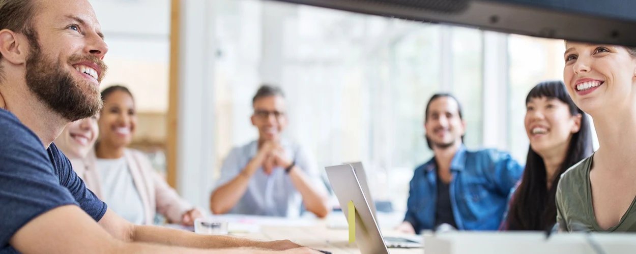 Junge Menschen arbeiten gemeinsam im modernen Büro an einem Laptop und wirken motiviert.