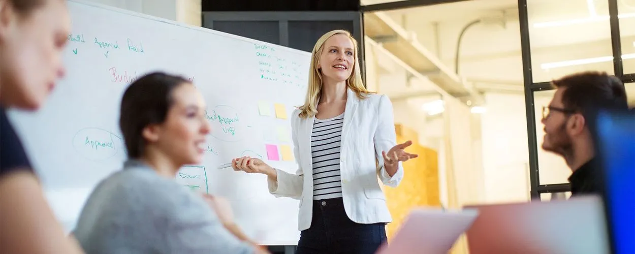 Eine Frau präsentiert Geschäftsideen an einem Whiteboard in einem modernen Büro.